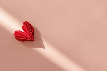 Happy Valentine's day! Stylish red heart in sunlight on pink paper background flat lay. Modern cute...