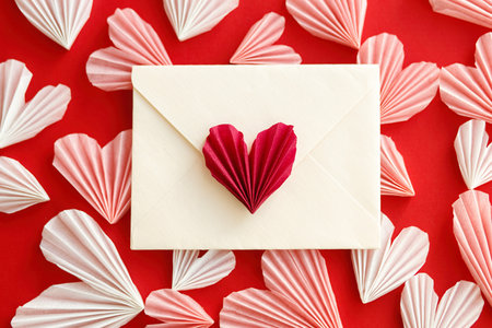 Valentines day flat lay. Stylish envelope with pink and red hearts composition on red paper...