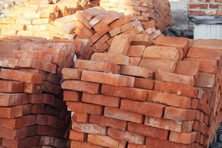 Stack of red bricks, process of house building. Bricks for laying on concrete foundation. Building...