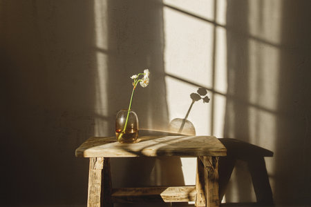 Beautiful daffodils in vase on rustic wooden bench on background of modern room in sunlight. Bridal daffodil close up. Stylish farmhouse home decor. Atmospheric spring flowersの写真素材