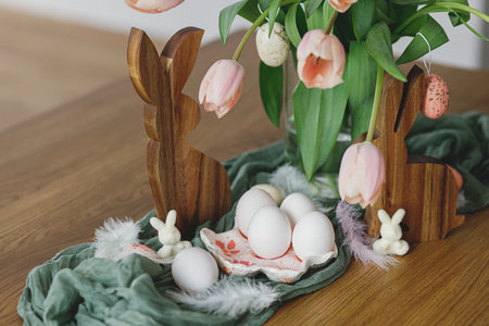 Beautiful tulips, eggs and bunny decoration on wooden table. Modern farmhouse easter decor. Happy Easter! Stylish handmade egg holder, natural eggs, pink tulips bouquet and rustic bunniesの写真素材