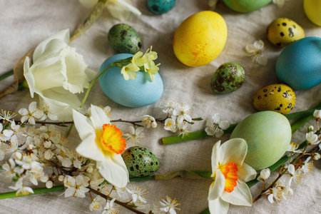 Stylish easter eggs and blooming spring flowers on rustic table. Happy Easter! Rustic easter still...