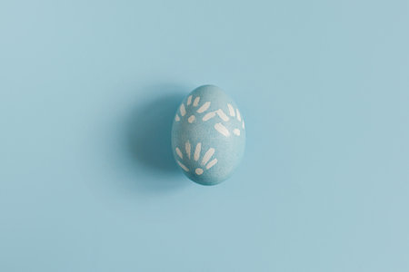 Happy Easter! Easter egg on blue background flat lay. Minimal Easter still life. Modern spring...