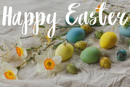 Happy Easter greeting card. Happy Easter text on stylish easter eggs and blooming spring flowers on rustic table. Modern Greeting card. Handwritten signの写真素材