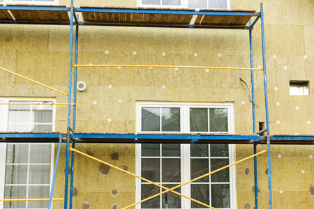 House insulation concept. Facade insulation with mineral wool, thermal improvement and energy saving. Modern farmhouse renovation, scaffolding platform and stone wool panelsの写真素材