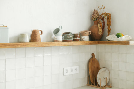 Modern kitchen interior. Stylish kitchen with wooden shelves with utensils and cups in new...