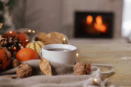 Cozy autumn. Warm cup of tea, pumpkins, autumn leaves, cones, cozy scarf and lights on rustic wooden table in farmhouse. Fall in rural home. Happy Thanksgiving. Fall hygge still life, bannerの写真素材