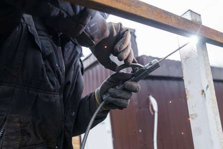 Shielded metal arc welding. Worker welding metal with electrodes, wearing protective helmet and...