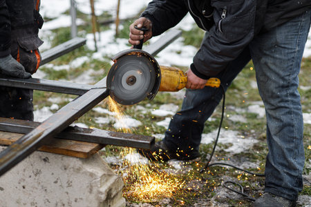 Close up of man grinding metal with circular grinder disc and electric sparks. Worker cutting metal...