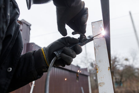 Welder man welding metal iron with electrodes, worker wearing protective helmet and gloves. Close up of electrode welding and electric sparks. Shielded metal arc weldingの写真素材