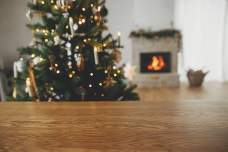 Christmas festive template and wooden board mock up for product. Stylish wooden table against christmas tree with lights and burning fireplace. Christmas background, copy spaceの写真素材