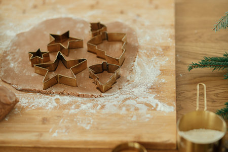 Making christmas gingerbread cookies, atmospheric holiday time. Gingerbread dough with golden cutters, rolling pin, fir branches and festive decorations on rustic wooden tableの写真素材