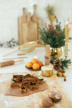 Making christmas gingerbread cookies. Gingerbread dough with festive golden metal cutters on wooden...