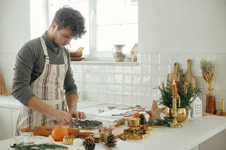 Man making christmas gingerbread cookies close up in modern white kitchen. Hands cutting gingerbread...