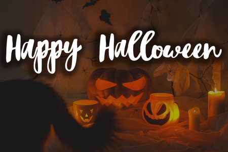 Happy Halloween! Happy Halloween text and spooky Jack o lantern pumpkin,cat tail silhouette, spider web with glowing lights in dark. Scary atmospheric halloween greeting card, handwritten signの写真素材