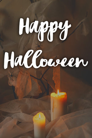 Happy Halloween! Happy Halloween text and spooky spider web with glowing candles in dark. Scary atmospheric halloween greeting card, handwritten signの写真素材