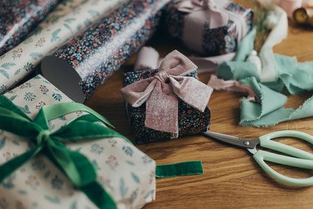 Wrapping christmas gifts. Stylish present, festive wrapping paper, ribbons, scissors, vintage...