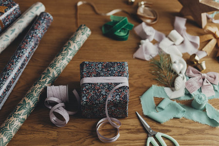 Wrapping christmas gifts. Stylish present, festive wrapping paper, ribbons, scissors, vintage...