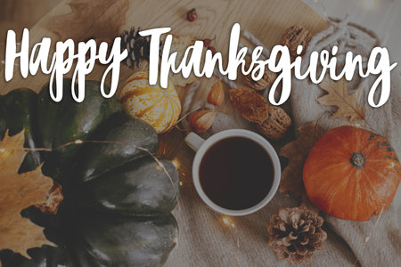 Happy Thanksgiving! Happy thanksgiving text and warm cup of tea, pumpkins, fall leaves, cozy scarf and lights on rustic table. Season Greeting card, handwritten sign. Give thanksの写真素材