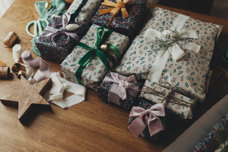 Stylish christmas gifts, festive wrapping paper, ribbons, vintage ornaments, brass bells on wooden table. Merry Christmas! Atmospheric winter holidays preparationの写真素材
