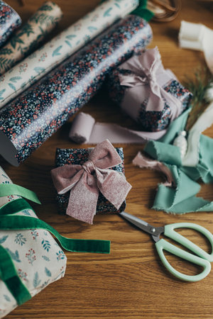 Stylish christmas gift, festive wrapping paper, ribbons, scissors, vintage ornaments and brass bells on wooden table. Wrapping christmas present. Merry Christmas! Winter holiday preparationの写真素材