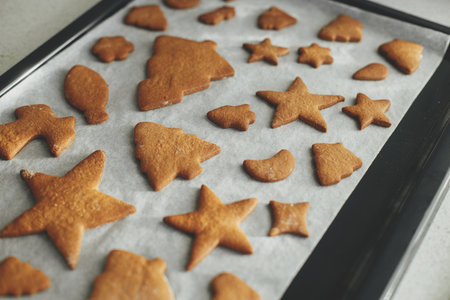 Fresh baked gingerbread cookies in christmas festive shapes on baking tray in modern white kitchen. Making christmas gingerbread cookiesの写真素材