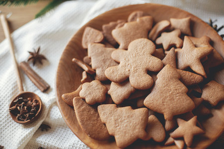 Christmas gingerbread cookies in wooden plate on rustic table flat lay with spices. Merry Christmas! Delicious fresh gingerbread cookies close up, atmospheric holidayの写真素材