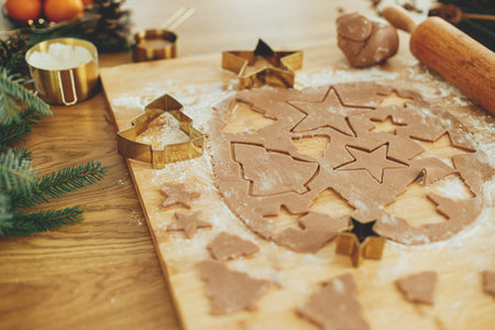 Gingerbread dough with golden cutters, rolling pin, cooking spices and festive decorations on rustic wooden table. Making christmas gingerbread cookies, atmospheric holiday timeの写真素材