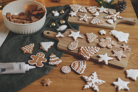 Gingerbread cookies with icing on rustic wooden table with festive decor. Christmas holiday traditions, atmospheric family time. Decorating cookies with sugar frostingの写真素材