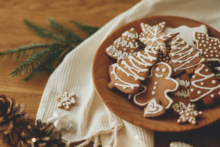 Merry Christmas! Gingerbread cookies with icing in plate on wooden rustic table with fir branches and festive decorations. Atmospheric Christmas holidays, family timeの写真素材