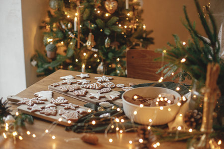 Christmas gingerbread cookies with icing on festive rustic  table with decorations against golden tree lights. Merry Christmas! Delicious gingerbread cookies, atmospheric holiday eveの写真素材