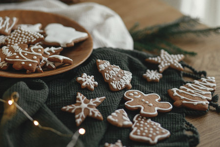 Christmas gingerbread cookies with icing on festive rustic table with decorations, fir branches, golden illumination. Merry Christmas! Delicious gingerbread cookies, atmospheric timeの写真素材
