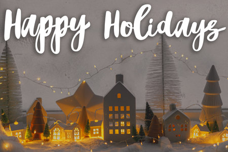 Happy Holidays text on cozy christmas miniature village with glowing lights in evening. Merry Christmas. Season's greeting card. Handwritten signの写真素材