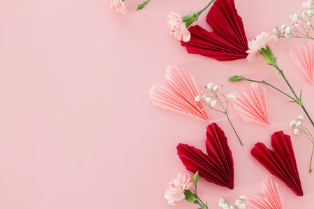 Happy Valentine's day ! Stylish pink and red hearts with gentle flowers flat lay on pink background. Valentines hearts paper cutouts. Love background with space for textの写真素材