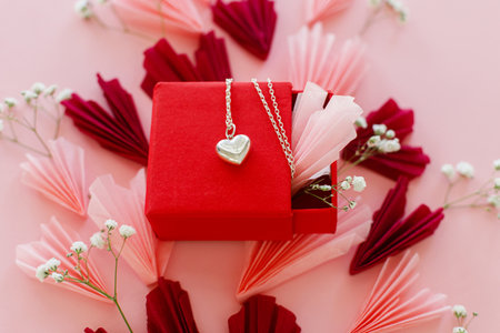 Valentines day. Stylish pink and red hearts, flowers and heart necklace on pink background. Happy Valentines day! Modern hearts paper cutouts and jewellery gift. Love and mother's dayの写真素材