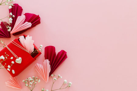Happy Valentine's day ! Stylish pink and red hearts, flowers and heart necklace flat lay on pink background. Valentines hearts paper cutouts and jewelry gift. Love and mother's dayの写真素材