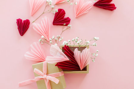 Valentines day flat lay. Stylish pink and red hearts, flowers and gift box on pink background. Happy Valentines day! Modern hearts paper cutouts from craft box. Love and mother's dayの写真素材