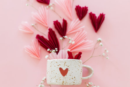 Happy Valentine's day ! Stylish pink and red hearts, flowers and modern cup with heart flat lay on pink background. Valentines hearts paper cutouts and mug. Love and mother's dayの写真素材