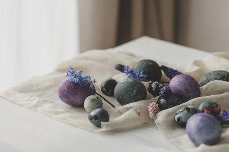 Stylish easter eggs, gentle spring flowers and linen cloth on rustic white table. Space for text. Happy Easter! Natural painted marble and purple eggs. Seasons greetingsの写真素材