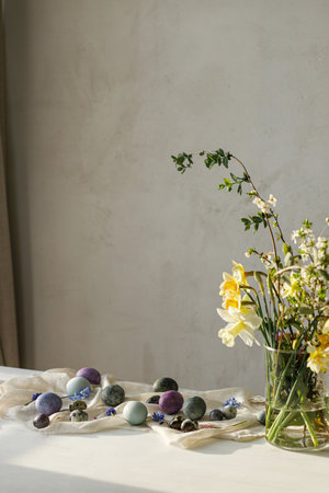 Stylish easter eggs and spring flowers bouquet on rustic wooden table. Easter modern simple decor,...