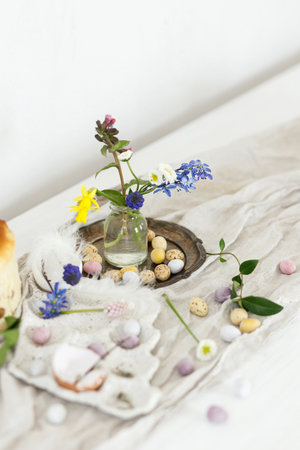 Colorful easter chocolate eggs, easter bread, spring flowers and linen cloth on rustic wooden table. Easter modern simple decoration and homemade traditional cake. Happy Easter!の写真素材