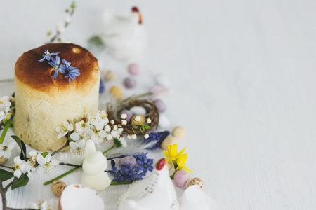 Happy Easter! Stylish easter chocolate eggs in nest, spring flowers, traditional bread on rustic...