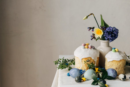 Stylish easter eggs, panettone, spring flowers and chocolate eggs on rustic wooden table. Natural dye marble eggs, blossom and holiday food. Space for text. Happy Easter!の写真素材
