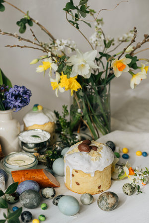 Happy Easter! Stylish easter natural dyed eggs, meat, bread, butter, beets, basket and flowers on rustic table. Traditional easter orthodox holiday food for blessing and daffodils bouquetの写真素材