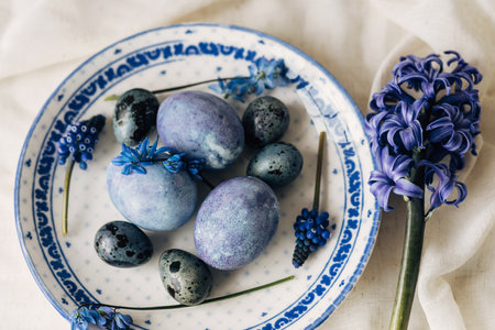 Happy Easter! Stylish easter eggs on vintage plate and spring flowers on linen napkin, rustic table setting. Natural painted blue eggs and hyacinth blooms. Modern minimal flat layの写真素材