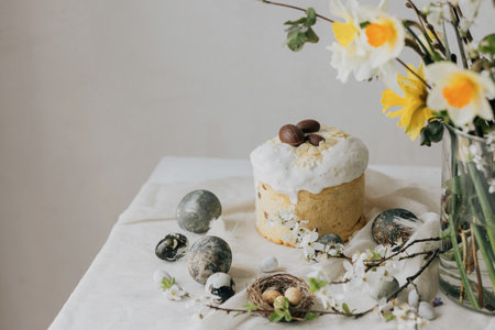 Happy Easter! Stylish easter eggs, homemade easter bread and spring flowers on linen napkin on rustic table. Natural painted marble eggs and cherry blooms, minimal still lifeの写真素材