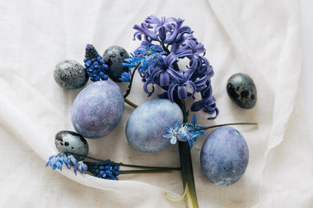 Stylish easter eggs and spring flowers on rustic wooden table. Happy Easter! Natural dye marble and blue eggs, purple hiacynt blossoms. Minimal still life.の写真素材
