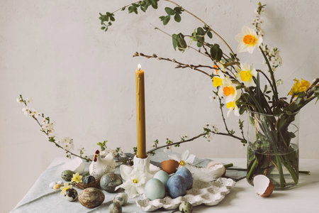 Happy Easter! Stylish easter eggs in tray, cherry blossom and candle on rustic table. Modern natural dyed marble eggs and spring flowers. Easter still life in countryside homeの写真素材