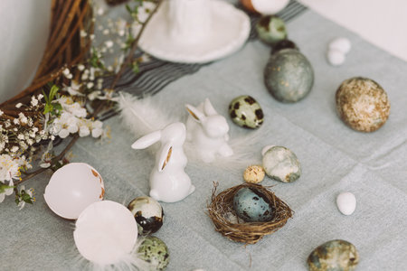 Stylish easter eggs, bunnies and cherry blossom composition on rustic table. Happy Easter! Modern natural dyed marble eggs and spring flowers. Rural still lifeの写真素材