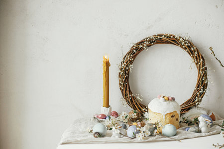 Happy Easter! Stylish easter eggs, cake, bunnies, cherry blossom and daffodils on rustic table. Modern natural dyed eggs, holiday food and spring flowers. Easter countryside still lifeの写真素材